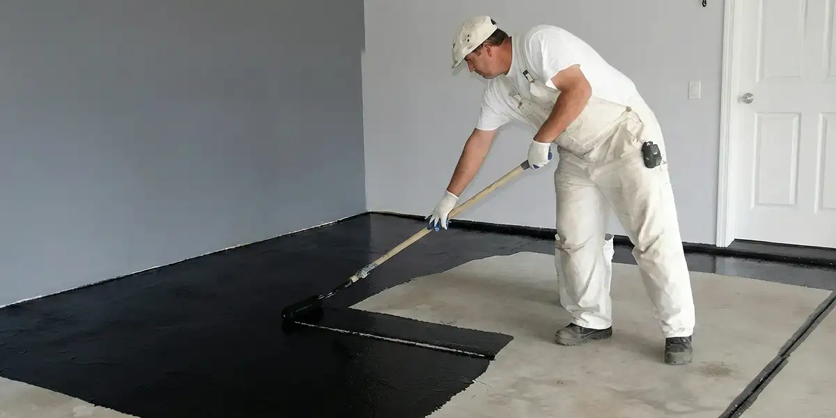 basement waterproofing professional applying waterproof coating to protect a basement floor in Tacoma, WA